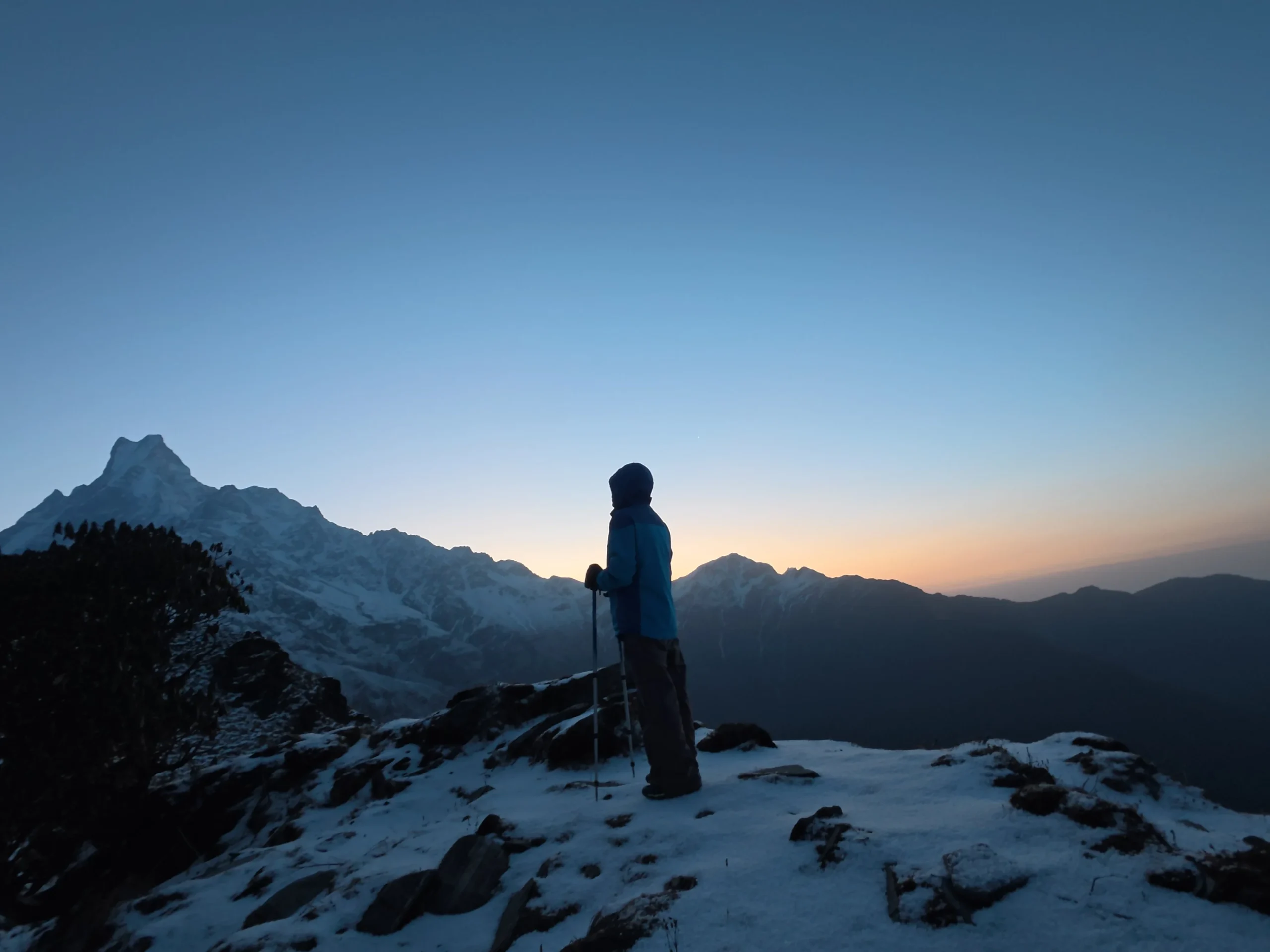 Trekker standing on a snowy Mardi Himal trail at sunrise with Machhapuchhre in the background